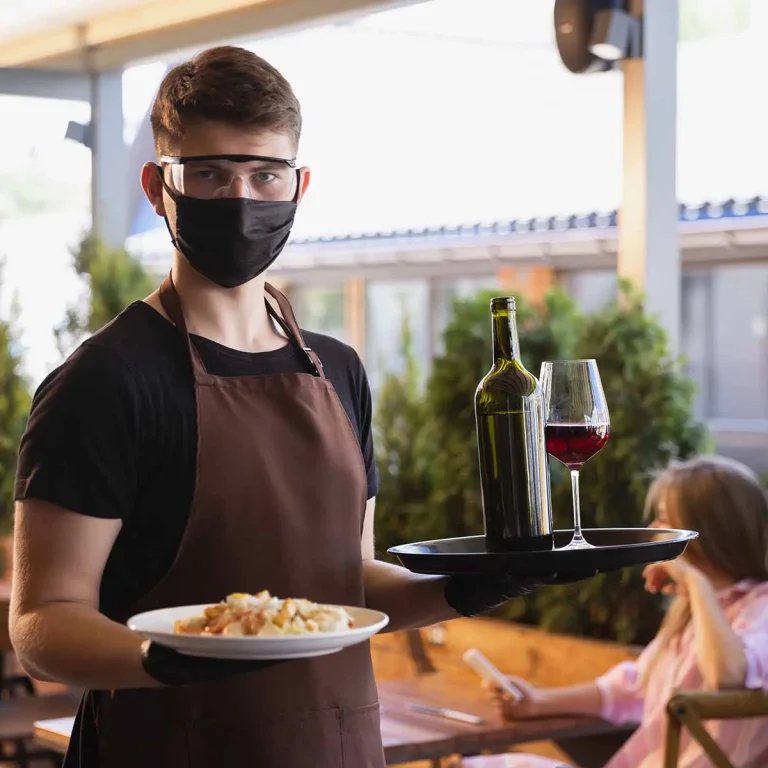 Restaurateur avec une assieste et un verre de vin, la fin du masque approche